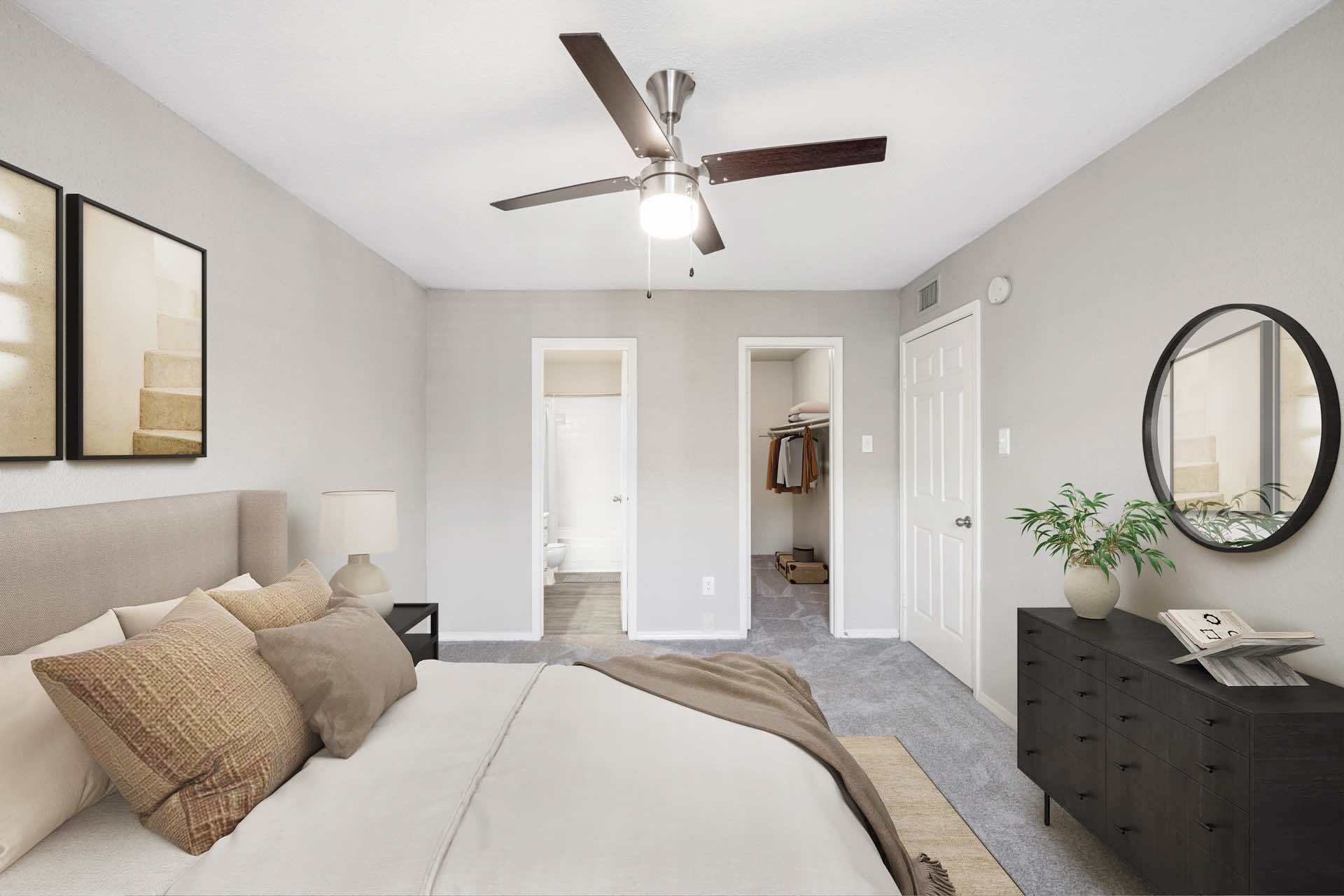 bedroom with ceiling fan, dark colored drawers and round mirror on wall