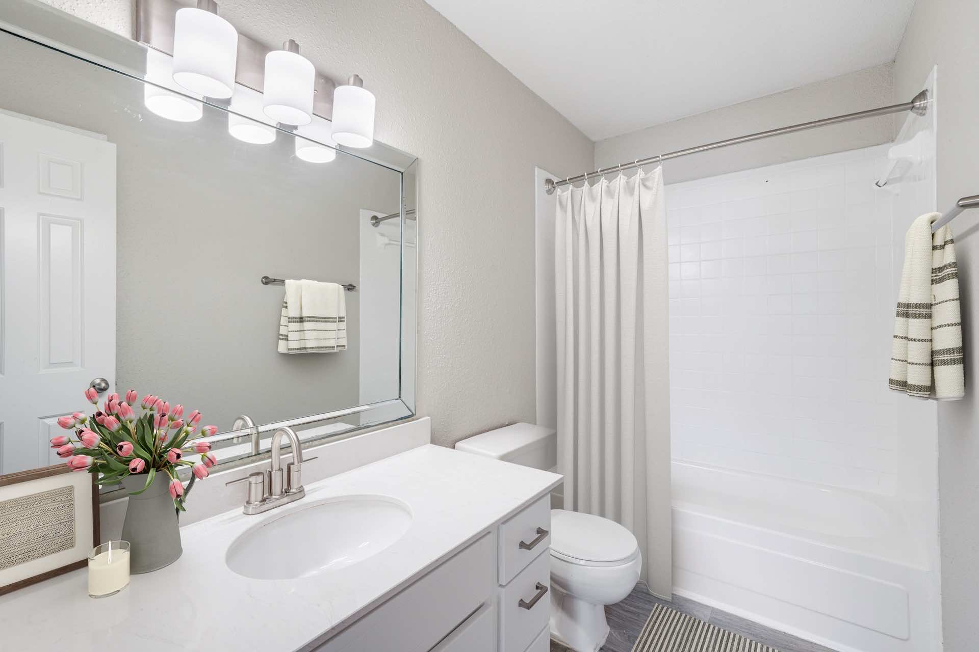 bathroom with updated counter top, lighting and curved shower rod