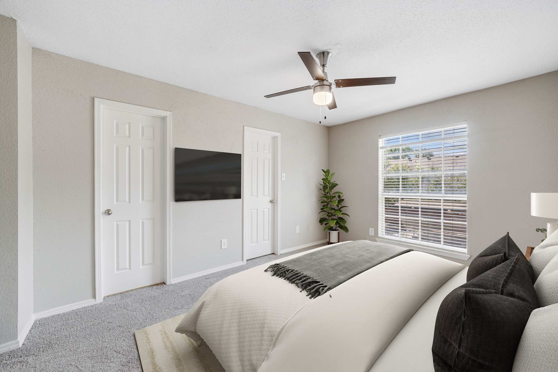 ceiling fan, wall-mounted tv, and large window in bedroom